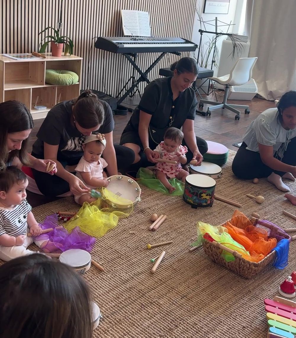 A Journeys class: babies and their moms on the rug with tambourines, drums and scarves
