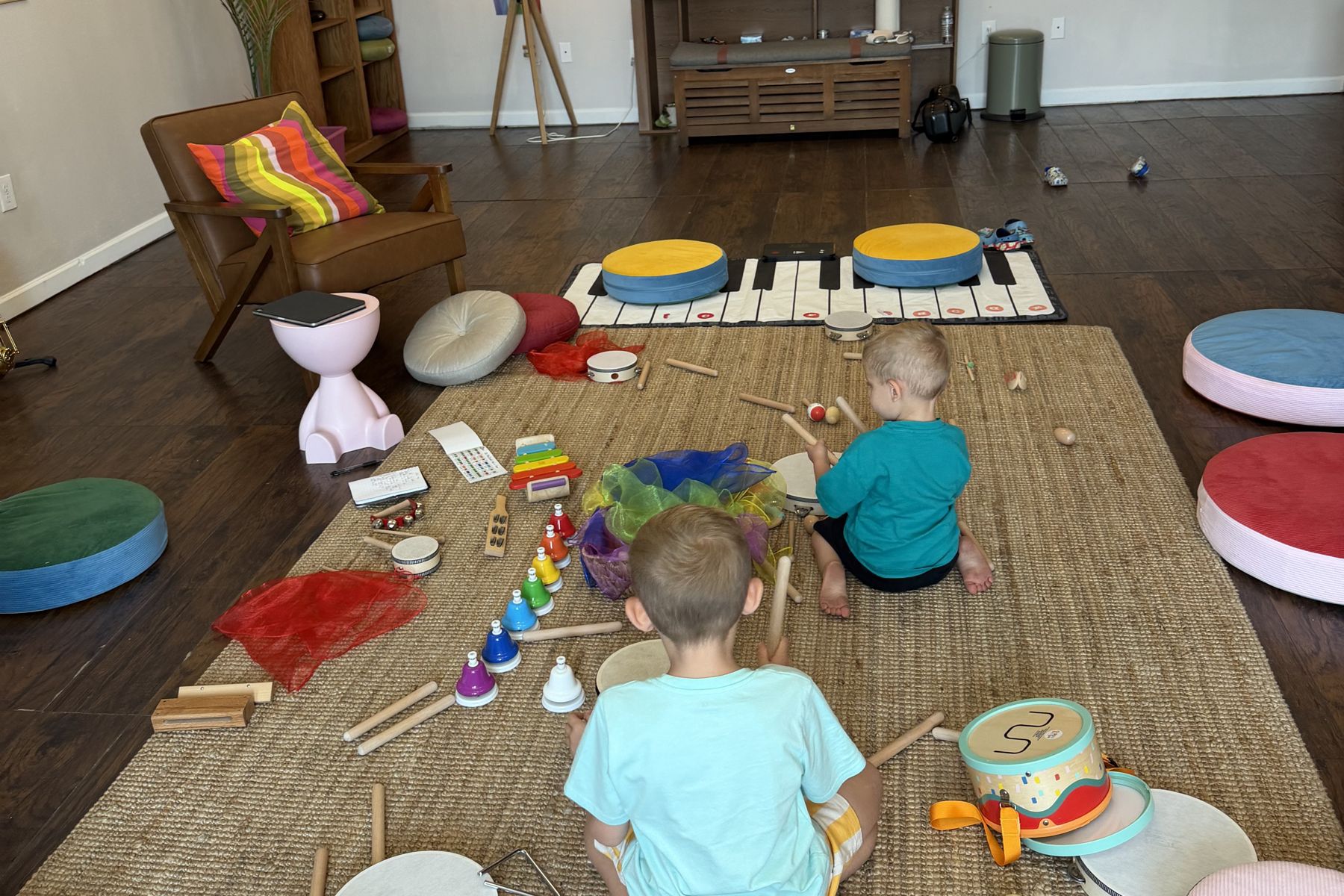 Inside The Nest: the class rug with drums, bells, scarves and cushions, and two children playing